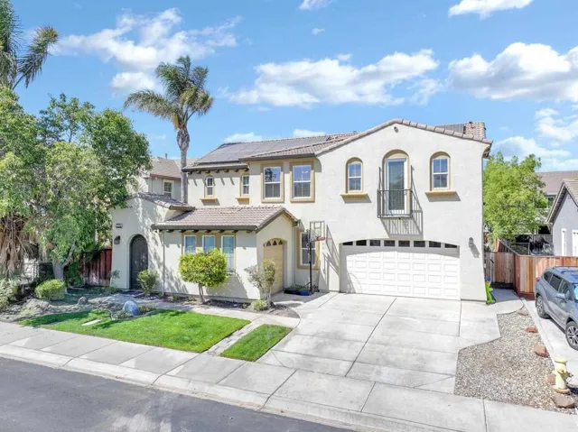 Mediterranean / spanish home with stucco siding, driveway, an attached garage, a tile roof, and roof mounted solar panels