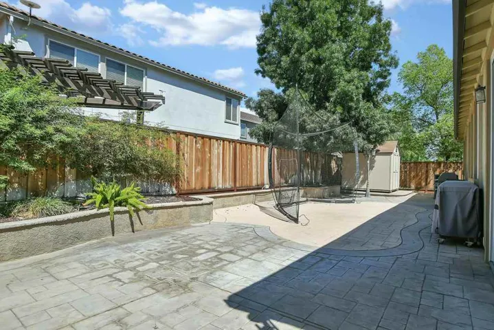 Fenced backyard with a storage shed, a patio, and area for grilling