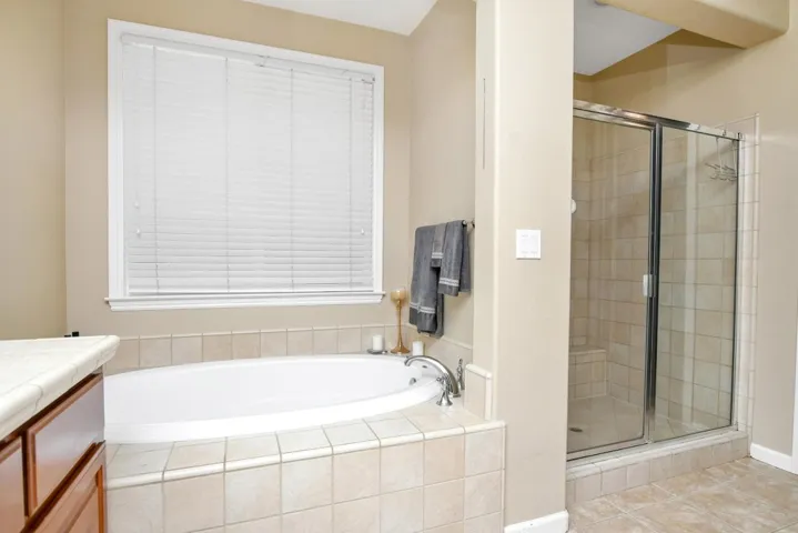 Bathroom with a shower stall, a garden tub, vanity, and light tile patterned floors