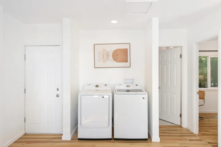 Laundry room with light wood-style floors, separate washer and dryer, and recessed lighting