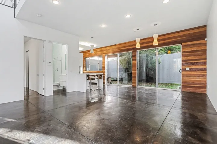 Unfurnished living room with finished concrete flooring, wood walls, and recessed lighting