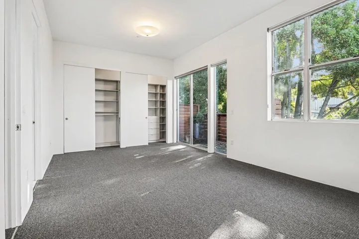 Unfurnished bedroom with two closets, carpet, and access to exterior