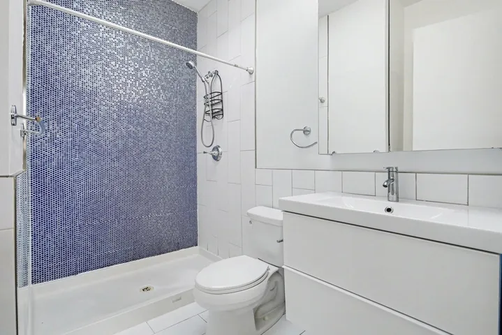 Full bath featuring tile walls, a shower stall, vanity, and tile patterned floors