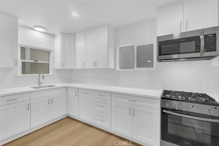 Kitchen view of the range, microwave, quarts counters and sink