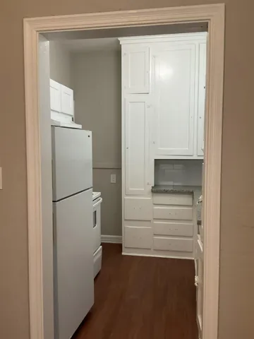 Kitchen featuring white cabinetry, white appliances, and dark wood finished floors