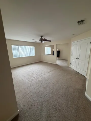 Carpeted spare room with baseboards and a ceiling fan