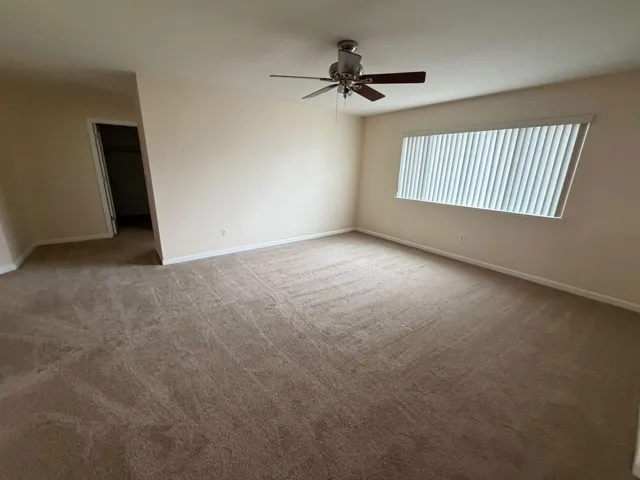 Unfurnished room with light colored carpet and a ceiling fan