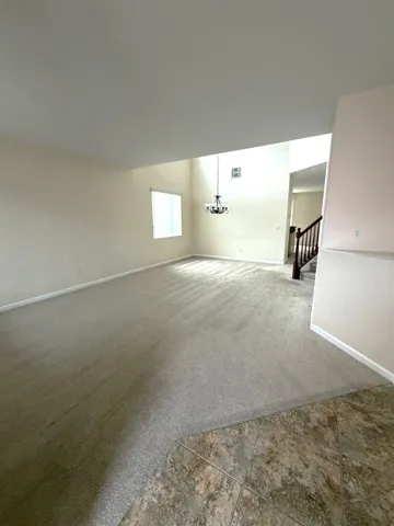 Unfurnished room with carpet, a chandelier, and tile patterned flooring