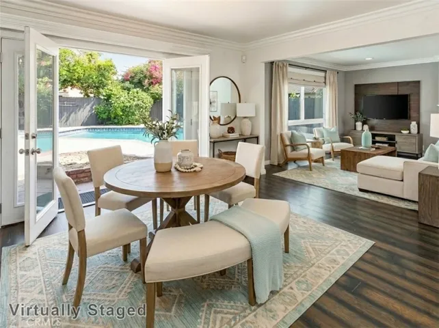 The formal dining room adjoins the kitchen and features crown molding, French doors with sidelights that open, and gleaming wood laminate floors, making it ideal for both everyday meals and special gatherings. Virtually staged/enhanced photo