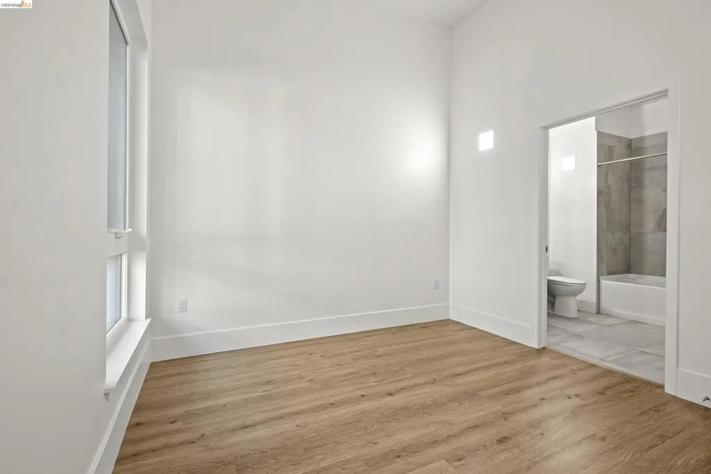 Unfurnished bedroom featuring wood finished floors and ensuite bathroom