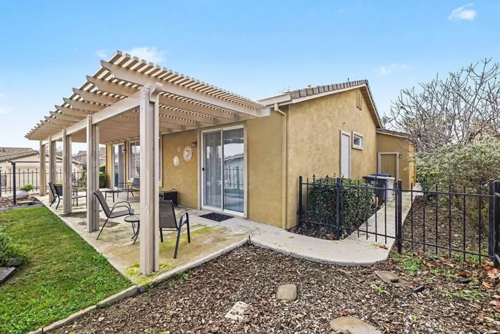 Rear view of house featuring stucco siding, a fenced backyard, a pergola, and a patio