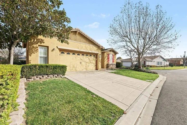 View of front of house featuring a front yard, concrete driveway, stucco siding, and a garage