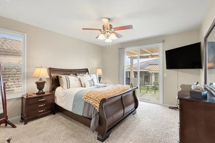 Bedroom with a ceiling fan, light colored carpet, and access to exterior