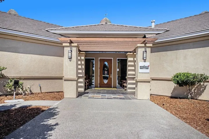 Property entrance with stucco siding, a chimney, and a tiled roof