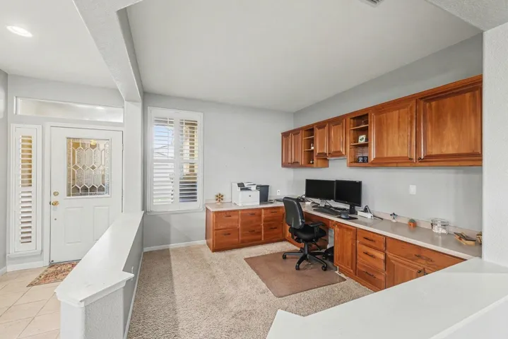 Office featuring light colored carpet, built in desk, and light tile patterned floors