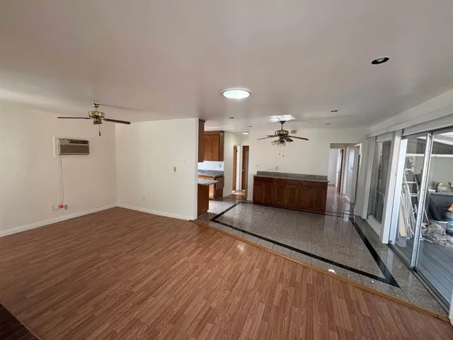 Unfurnished living room with ceiling fan, dark wood-style floors, and inlaid floor details