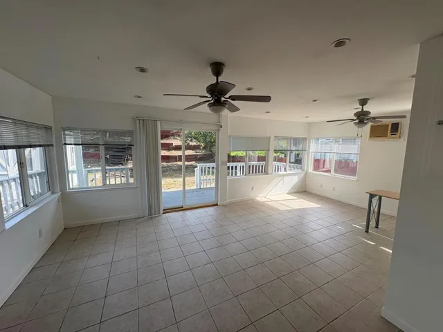 Unfurnished sunroom with tile patterned flooring and baseboards