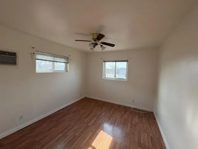 Unfurnished room with light wood-type flooring, healthy amount of natural light, and a ceiling fan
