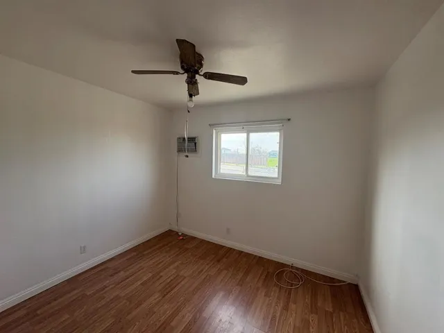 Empty room with wood finished floors and a ceiling fan