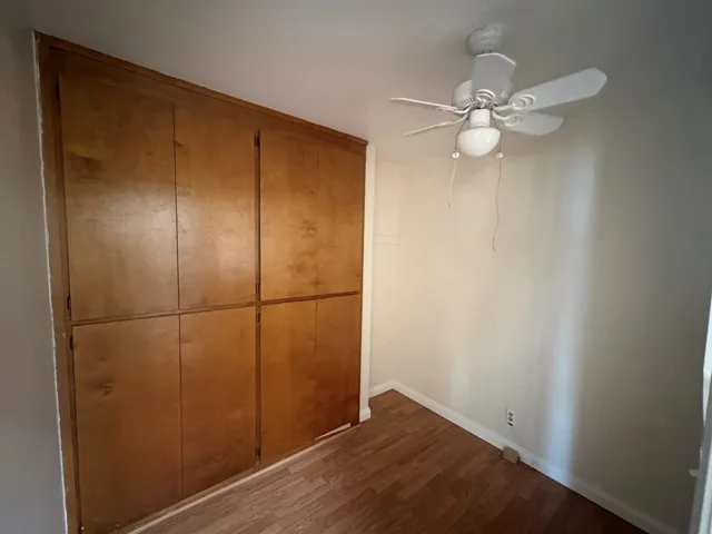 Unfurnished bedroom with dark wood-style flooring, a closet, and ceiling fan