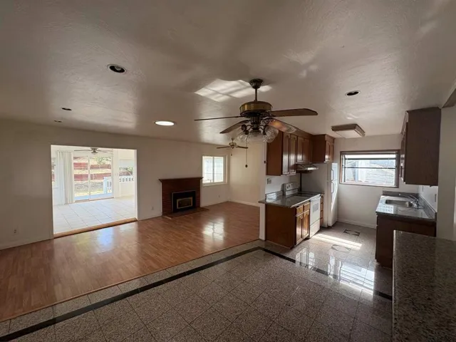 Kitchen with granite floors, white range with electric stovetop, open floor plan, a fireplace, and a ceiling fan