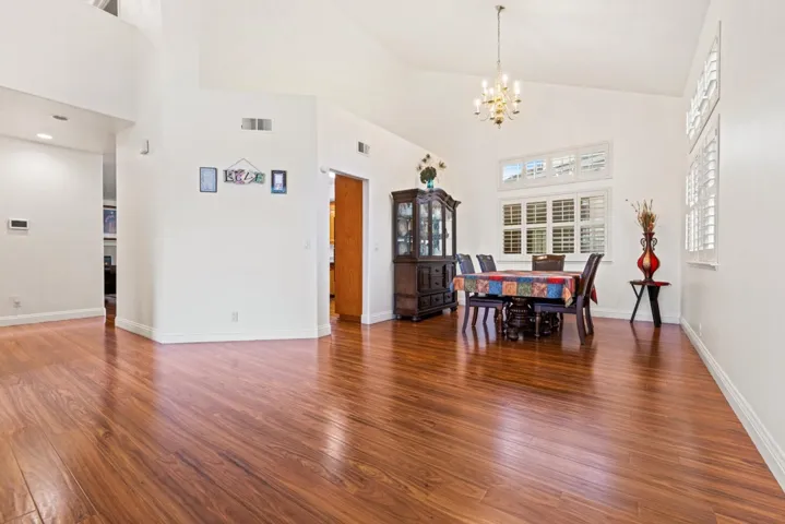 Dining room with hardwood / wood-style floors, a towering ceiling, and a​​‌​​​​‌​​‌‌​​‌​​​‌‌​​​‌​​‌‌​​‌‌​​‌‌​​​​ chandelier
