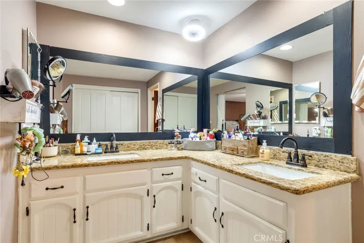 Primary bathroom includes a spacious dual-sink vanity with granite countertops and extensive mirror space.
