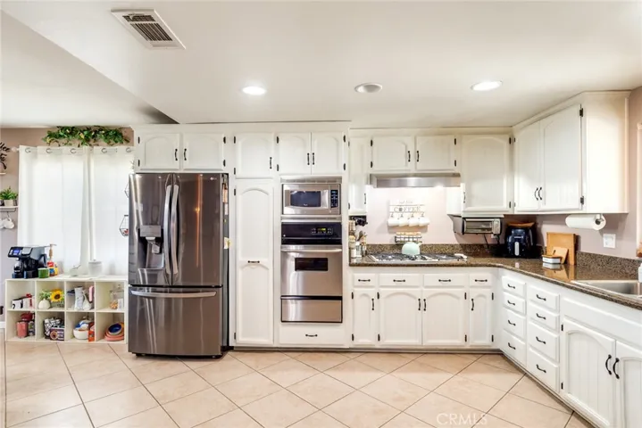 Kitchen features stainless steel appliances, a Whirlpool microwave, GE oven, and a five-burner gas cooktop.
The pantry includes convenient pull-out shelving for added organization.