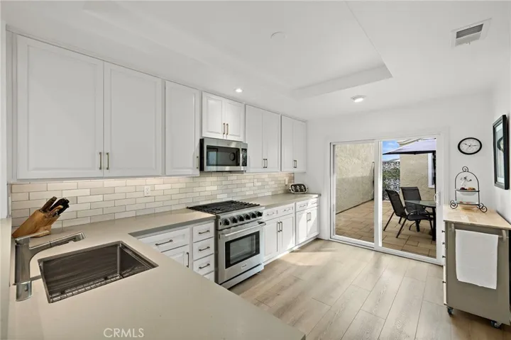 A beautifully designed gourmet kitchen showcases clean lines, abundant light, deluxe appliances, and a stylish bar that anchors the space.