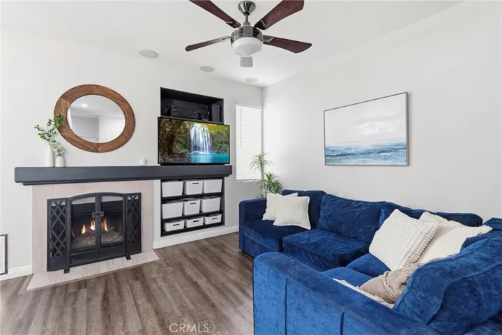 Relax in a bright, light-filled living room offering in-ceiling speakers, a cozy fireplace, and beautiful wood-look flooring.