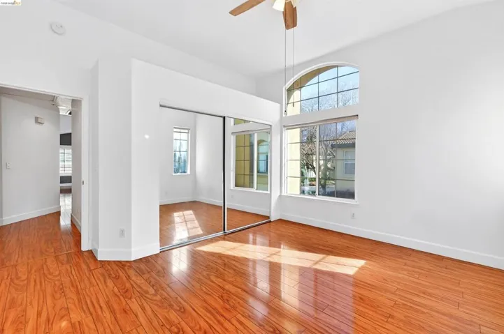 Unfurnished bedroom featuring light wood finished floors, a closet, ceiling fan, and a high ceiling