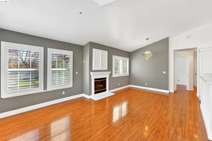 Unfurnished living room with lofted ceiling, light wood-type flooring, a glass covered fireplace, and a chandelier