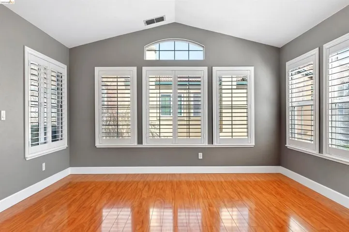 Unfurnished room with light wood finished floors and lofted ceiling