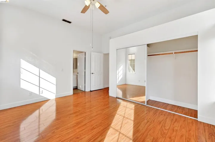 Unfurnished bedroom with light wood-style floors, a closet, a ceiling fan, and a towering ceiling