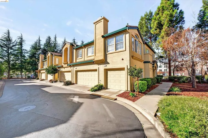 View of property exterior with stucco siding, a garage, a chimney, a residential view, and driveway