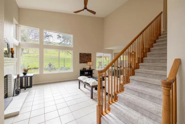 Stairway with a high ceiling, tile patterned floors, and a ceiling fan