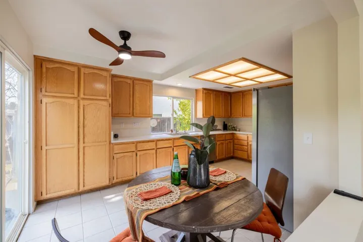 Kitchen with light countertops, ceiling fan, freestanding refrigerator, and light tile patterned floors