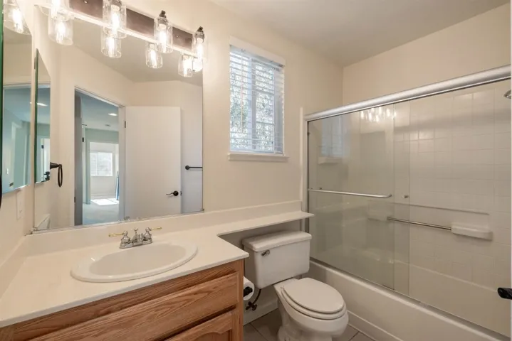 Bathroom featuring vanity and shower / bath combination with glass door