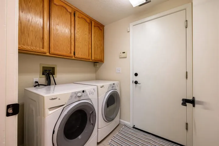 Laundry area with cabinet space, washing machine and dryer, and a textured ceiling