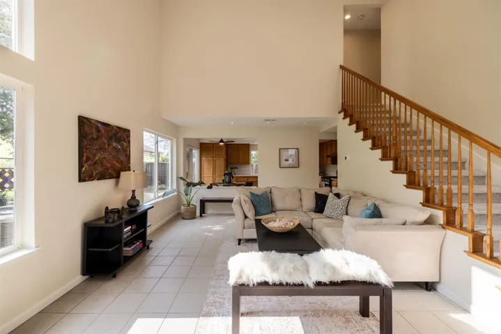 Living room with light tile patterned floors, a towering ceiling, and stairway