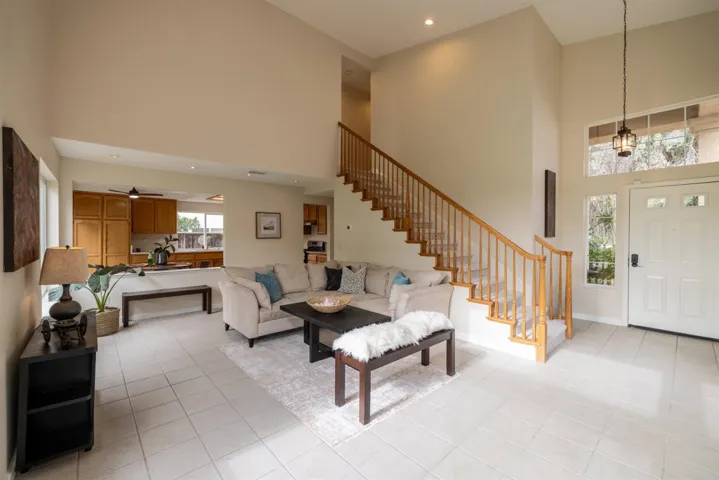 Living area featuring a towering ceiling, recessed lighting, light tile patterned flooring, and stairs