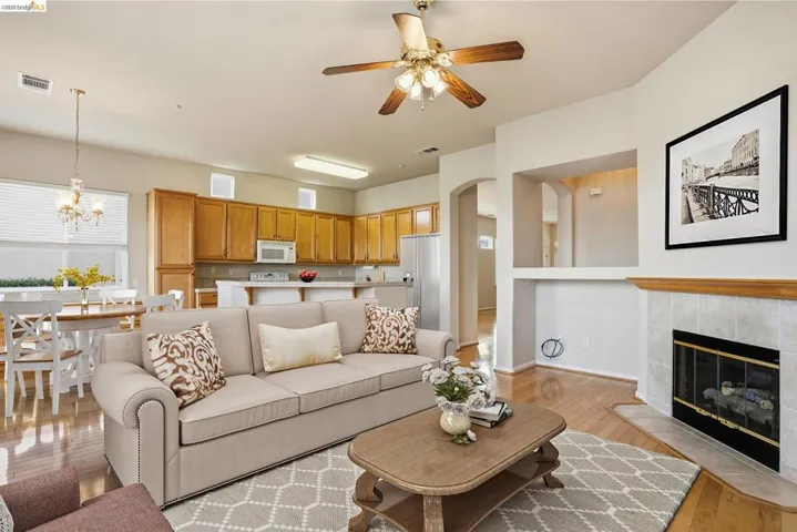 Family room with light wood finished floors, a fireplace, ceiling fan, arched walkways. Virtually staged to showcase how the space can come to life when you move in and make it your own.