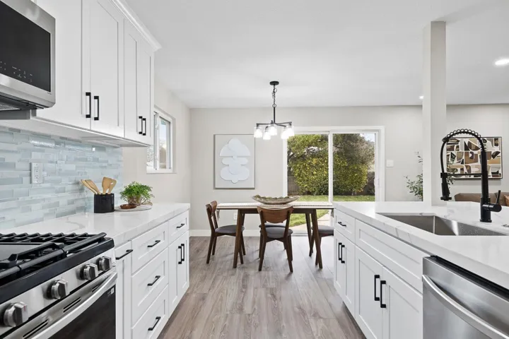 Kitchen with white cabinetry, appliances with stainless steel finishes, light wood-type flooring, pendant lighting, and tasteful backsplash