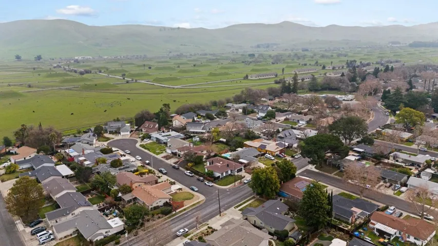 Aerial view of property and surrounding area with a mountainous background and nearby suburban area
