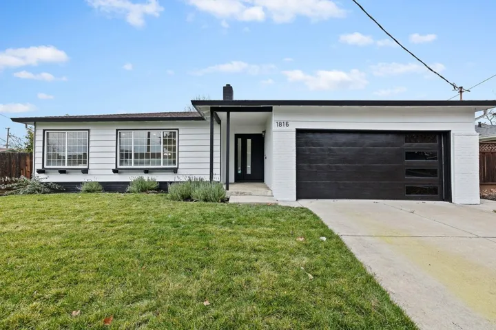 View of front of house with brick siding, a chimney, driveway, and a garage