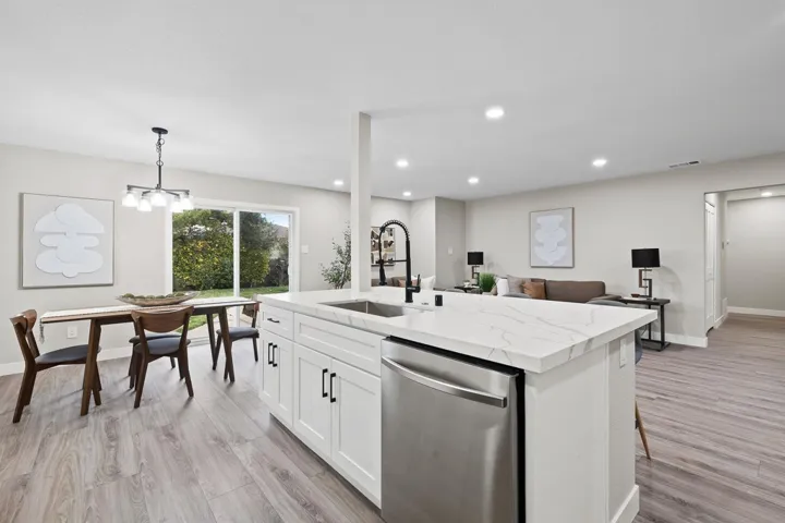Kitchen with stainless steel dishwasher, pendant lighting, light wood finished floors, a kitchen island with sink, and recessed lighting