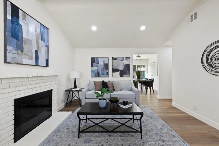 Living room with lofted ceiling, wood finished floors, a fireplace, and recessed lighting