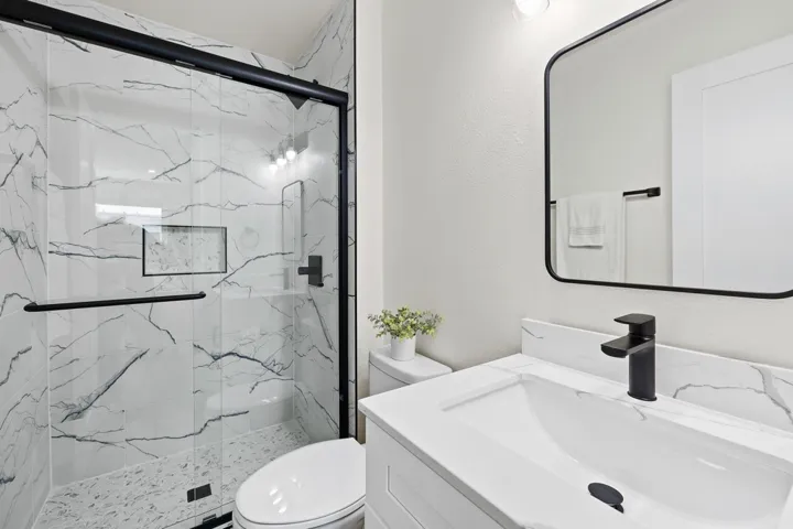 Bathroom with a marble finish shower, vanity, and a textured wall