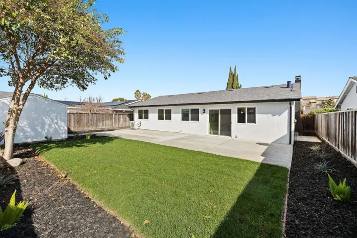 Rear view of house featuring a patio area, stucco siding, a fenced backyard, and a chimney