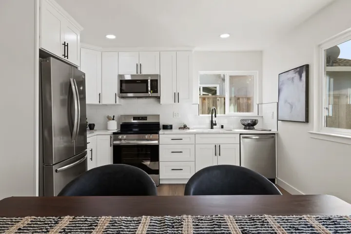Kitchen featuring stainless steel appliances, white cabinetry, decorative backsplash, and recessed lighting